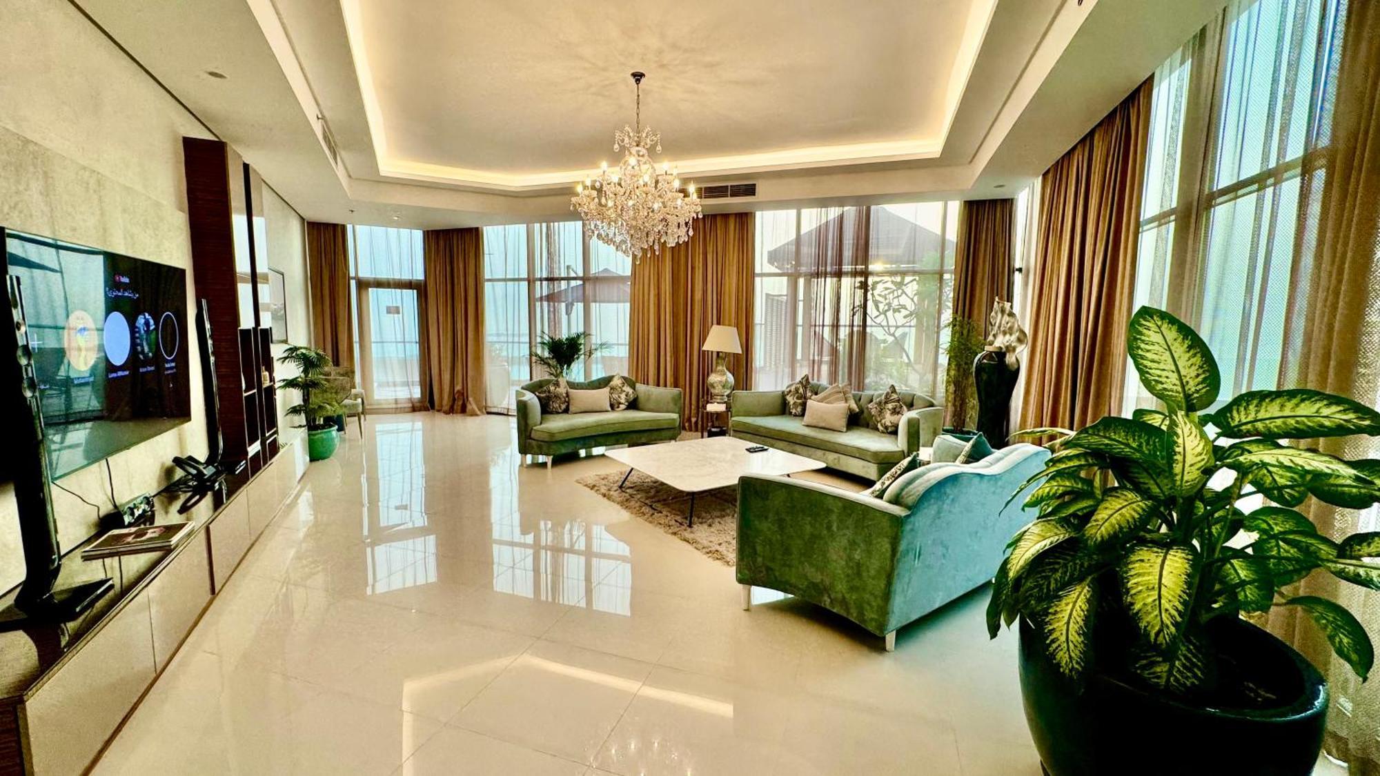 Lagoona Beach Luxury Resort And Spa Manáma Kültér fotó The photo depicts a spacious and elegantly designed living room. The room features large windows allowing natural light to flood in, accompanied by sumptuous curtains. The furniture includes a pair of soft green sofas and a centerpiece coffee table s
