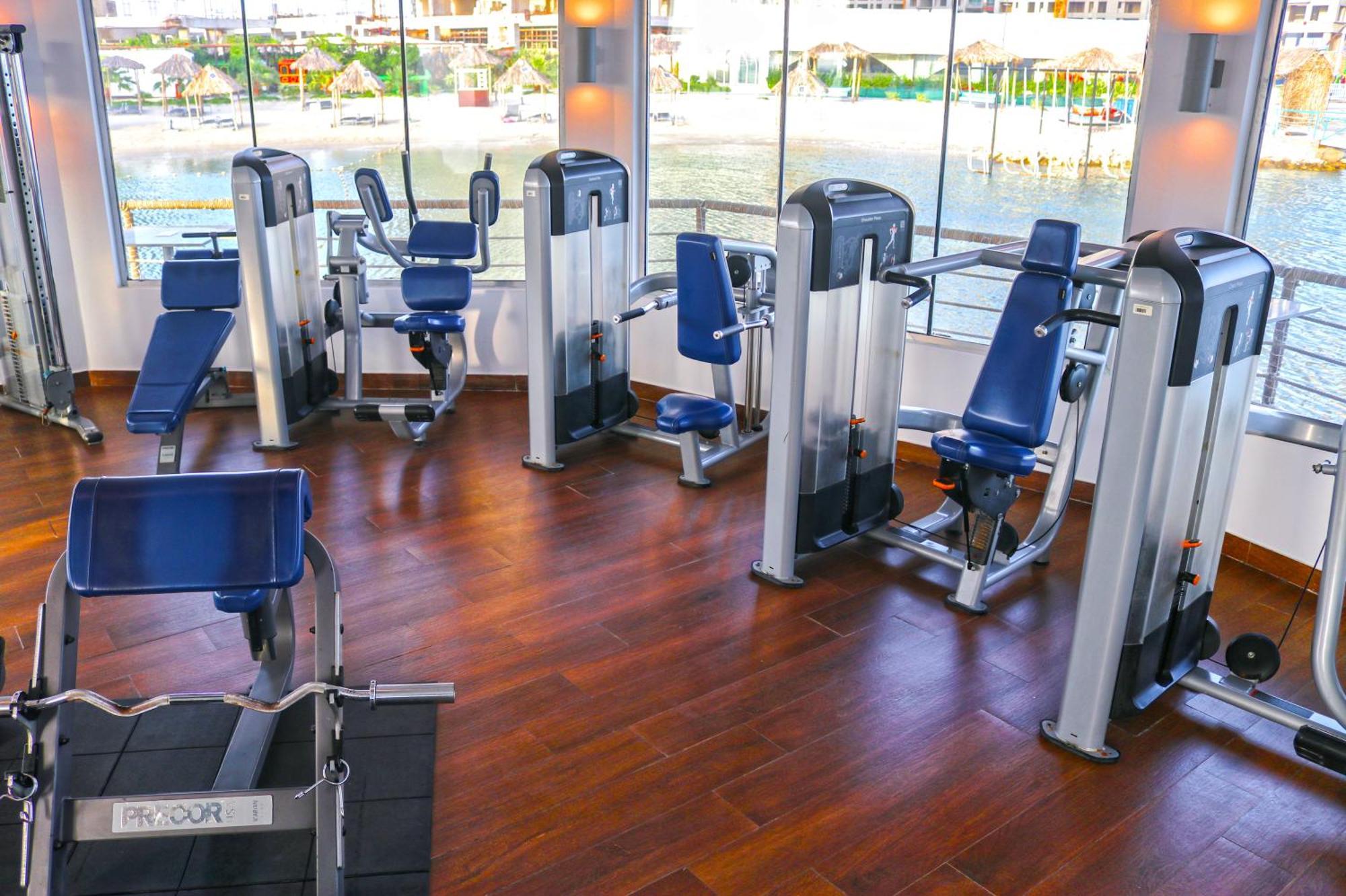 Lagoona Beach Luxury Resort And Spa Manáma Kültér fotó The photo shows a gym or fitness center with several pieces of exercise equipment. There are multiple machines designed for strength training, including seated machines with padded seats and backrests. The equipment appears to have a modern design an