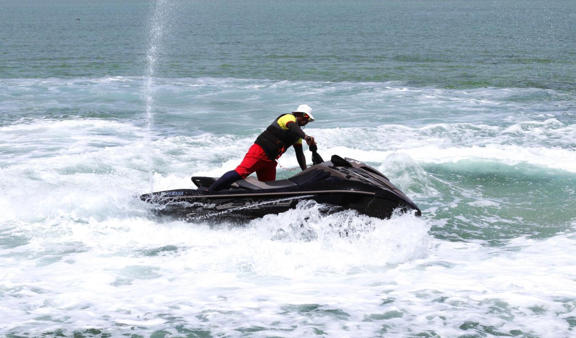 Lagoona Beach Luxury Resort And Spa Manáma Kültér fotó The photo shows a person riding a jet ski on the water. The rider is positioned upright, leaning forward with one hand on the handlebars, while the jet ski creates splashes of white foam around it. The water appears choppy, likely due to the motion o