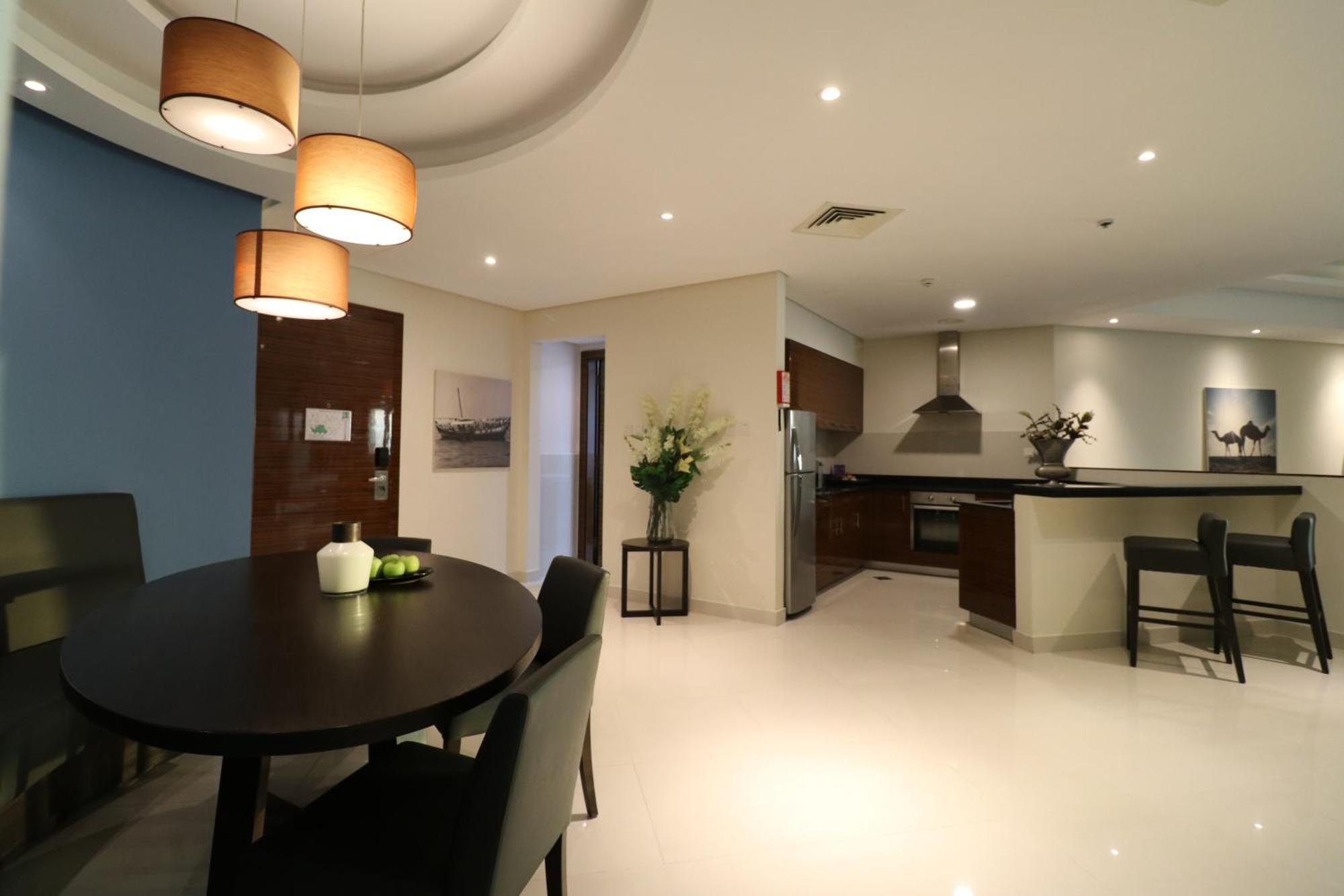 Lagoona Beach Luxury Resort And Spa Manáma Kültér fotó The photo shows a modern, open-concept dining and kitchen area. On the left, there is a round dining table with black chairs, accompanied by a few decorative elements like a small vase and some fruit. The walls have a combination of light and dark to