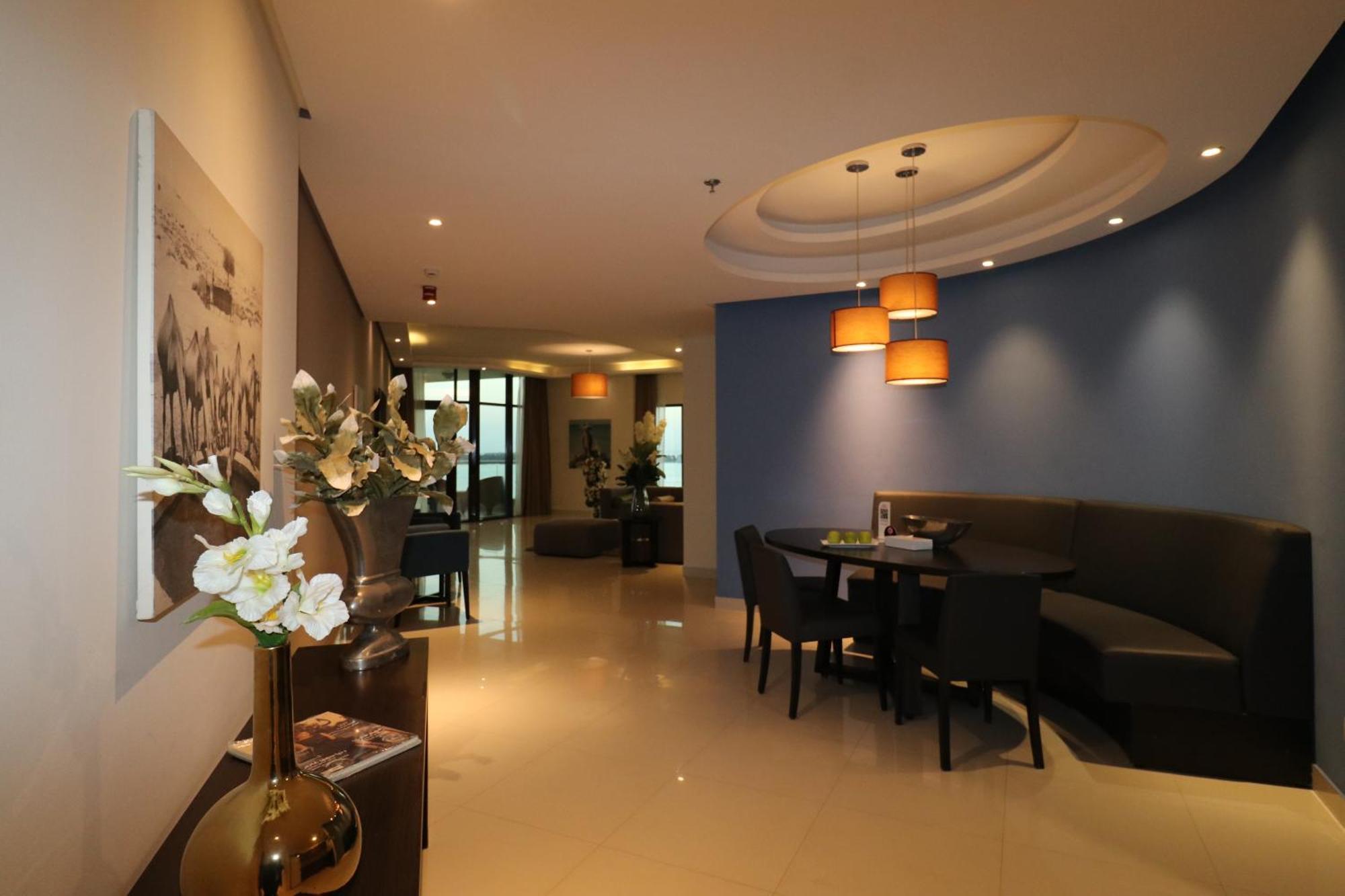 Lagoona Beach Luxury Resort And Spa Manáma Kültér fotó The photo showcases an interior space, likely a modern lounge or reception area. It features a combination of soft lighting, neutral-colored walls, and decorative elements. There are elegant light fixtures hanging from the ceiling, and a curved blue 